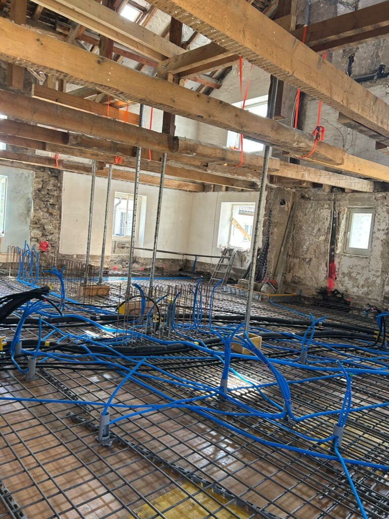 Intérieur d'un bâtiment en rénovation avec des tuyaux qui sont en train d'être posé