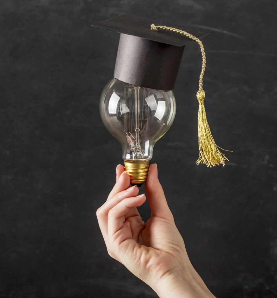 Une personne tenant une ampoule sur laquelle se trouve un petit chapeau noir de cérémonie de fin d'étude